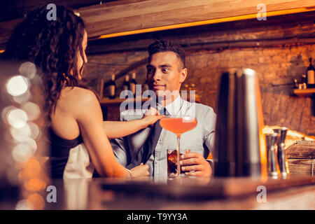Boyfriend making funny face while caring girlfriend fixing his tie Stock Photo