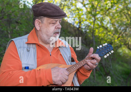 Outdoor portrait of senior man playing mandolin Stock Photo