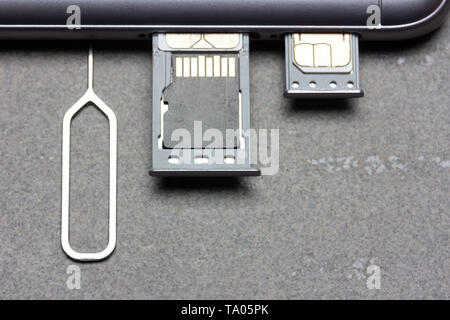 Smartphone with open SIM slots and micro SD memory on a gray background with copy space, top view close-up Stock Photo