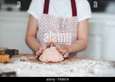 Girl kneading raw dough on table closeup. Cooking at kitchen. Stock Photo