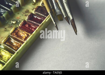 tools of the artist, professional watercolor paints in a box, brushes, on a white background