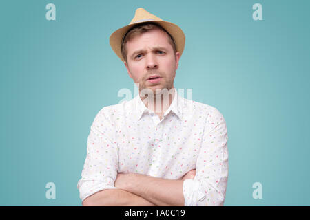 Young man in summer hat frowning showing disbelief or doubt. Stock Photo