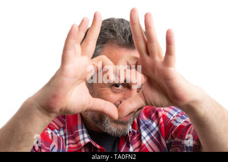 Closeup of casual man looking through heart shape made with fingers as love concept isolated on white studio background Stock Photo