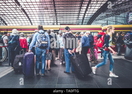 Berlin, Germany - May,  2019: Group of elder people with luggage at train station platform entering S-Bahn  train at Berlin Hauptnbahnhof