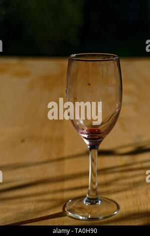 Fruit flies are attracted to a dirty red wine glass left on a table Stock Photo