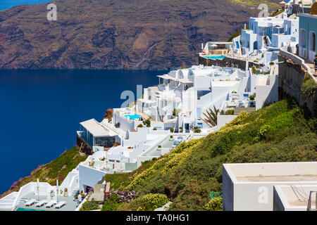 Santorini, Greece white houses architecture, hotels with caldera blue sea view and flowers blossom in famous island Stock Photo