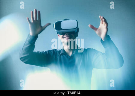 Young man in virtual glasses interacts with virtual reality and makes gestures. Stock Photo