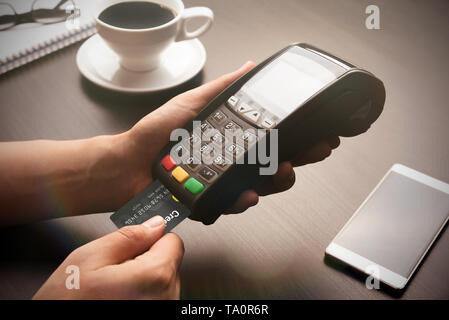 Man pays with the card in the restaurant. Payment terminal, POS device in hand Stock Photo