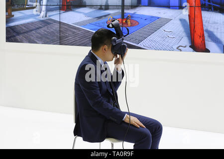A man in a business suit is sitting on a chair. The man is wearing virtual reality glasses. Helmet-glasses of additional reality are put on the person Stock Photo