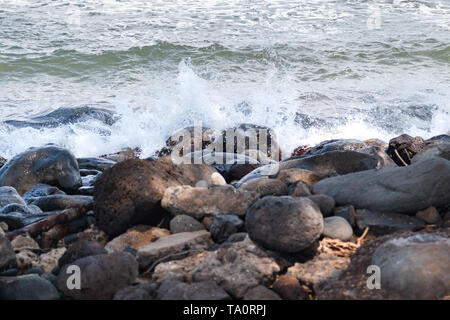 Wave splashing against rocks on a beach Stock Photo