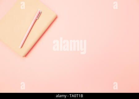 Beige diary with pink pen on pastel millennial pink paper background. Concept of education, blogging. Top view. Flat lay. Minimal style. Stock Photo