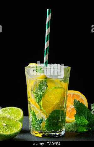 refreshing drink lemonade with lemons, mint leaves, ice cubes and lime in a glass on a black background Stock Photo
