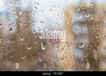 Rain drops on window glasses surface with with modern appartment building in background. Rainy day concept Stock Photo