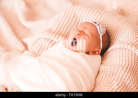 Yawning baby girl lying in bed close up. Good morning. Childhood.