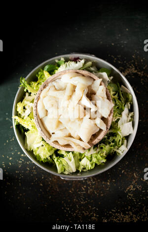 high angle view of some bowls with the ingredients to prepare xato, a catalan salad with desalinated salt cod and escarole endive, on a rustic dark gr Stock Photo