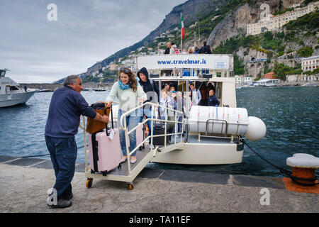 Boat transport. Woman tourist with luggage and other passengers disembarking from a Travelmar Ferry at the harbour in Amalfi on the Amalfi Coast. Stock Photo