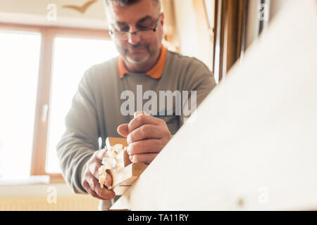 Experienced carpenter planing wood in workshop Stock Photo