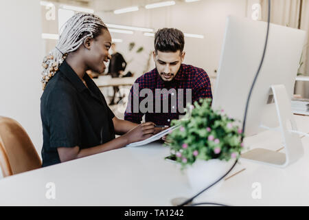Multiracial young creative people in modern office. Group of young people are working together with pc. Successful freelancers team in coworking. Indi Stock Photo