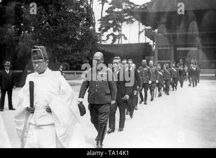 A group of military and MPs are leaving a shrine in Tokyo. The group is led by a man in ceremonial costume. Stock Photo