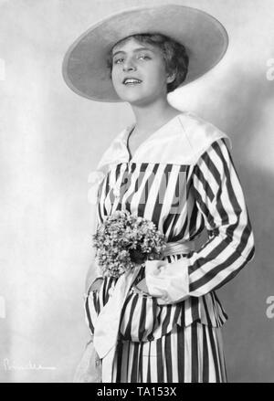 Mady Christians, a German actress, in a waisted striped jacket dress with front pockets and flowers in the waistband. Stock Photo