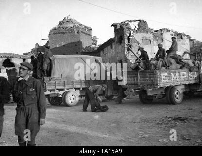 Photo of the city center of Belchite near Zaragoza, Aragon, Spain, in March, 1938. In the foreground, a Spanish national soldier. On the right behind there are trucks. In the background, houses shot to pieces. Stock Photo