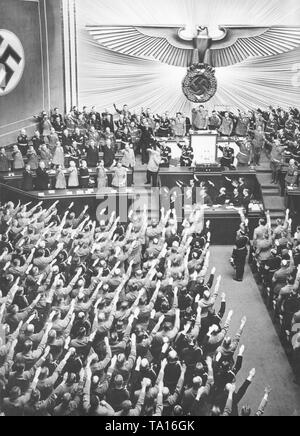 Adolf Hitler is greeted by deputies with the Nazi salute, at the meeting on the 6th anniversary of the seizure of power at the Berlin Kroll Opera House. Above, as President of the Reichstag, Hermann Goering, left in the government benches Johann Ludwig Graf Schwerin von Krosigk,Konstantin von Neurath, Joseph Goebbels, Wilhelm Frick, Joachim von Ribbentrop and Rudolf Hess. Above, Hans Frank, Franz Seldte, Hanns Kerrl, Bernhard Rust, Walther Darre, Franz Guertner, Hjalmar Schacht and Walther Funk, in the third row Hans Pfundtner, Fritz Todt, Johannes Popitz and Otto Meissner (each from left to Stock Photo