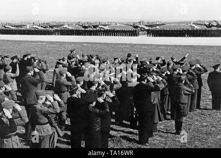 Photo of a parade of the Condor Legion on the airfield of Saragossa on the occasion of the Day of the Luftwaffe (airforce) on March the 1st, 1939. Soldiers have lined up on the airfield in the background. Behind, there are fighter aircrafts, type Messerschmitt Bf 109, and combat bombers, type Heinkel He 111. In the foreground German and Spanish soldiers are saluting. Stock Photo