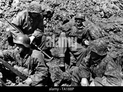 SS grenadiers rest in a bomb crater on the Mius-Front. Photo of the Propaganda Company (PK): SS war correspondent Adendorf. Stock Photo