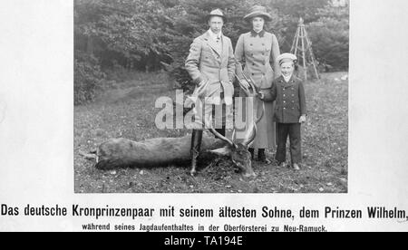 The Crown Prince Wilhelm (left) and Cecilie (mi.) with their eldest son, Prince Wilhelm (right), during a hunting stay at the Oberfoersterei zu Neu-Ramuck. The family stands next to a deer, that ws presumably killed by the Crown Prince. Stock Photo