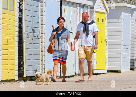 Lyme Regis, Dorset, UK.  21st May 2019. UK Weather.  A couple enjoying a stroll along seafront with their dog at the seaside resort of Lyme Regis in Dorset as they enjoy a warm sunny day.   Picture Credit: Graham Hunt/Alamy Live News Stock Photo