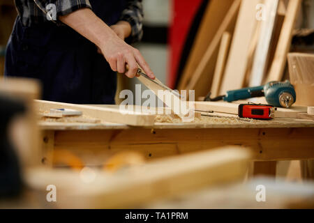 Closeup of unrecognizable carpenter carving wood while working in joinery lit by sunlight, copy space Stock Photo