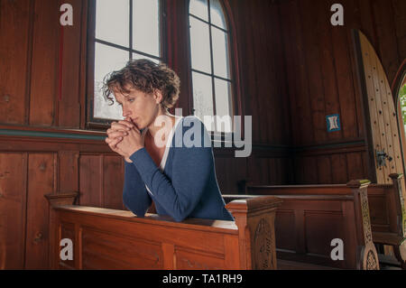Young woman prays in church Stock Photo