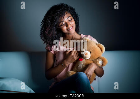 Portrait of black girl hugging teddy bear at night