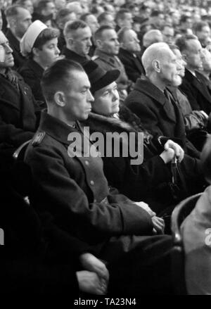 At a party rally of the NSDAP, Minister of Propaganda Joseph Goebbels gives a speech. In the audience sitting next to the party members, members of the Wehrmacht, wounded people and Red Cross nurses. Stock Photo