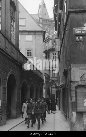 German soldiers march through Melantrichgasse in Prague. In the background, the Old Town Hall in Prague. Since the occupation in 1939, there had been many German soldiers in the Protectorate of Bohemia and Moravia. Stock Photo
