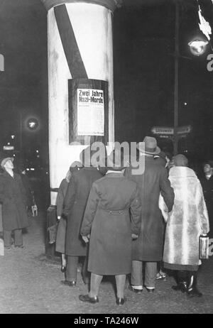 Citizens of Berlin look at a communist poster on an advertising column at the corner Potsdamer Strasse and Luetzowstrasse. The poster is trying to make use of the memory of the people killed in street battles with the Nazis since 1930, to set the mood against the Nazis. Stock Photo