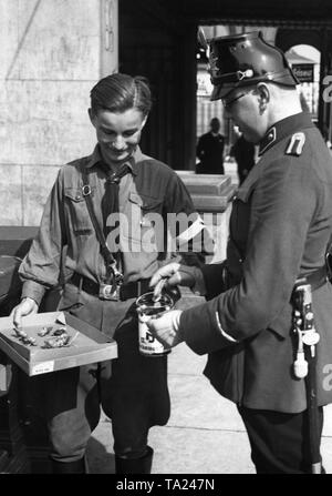 A member of the Hitlerjugend (Hitler Youth) collects donations for the 'Hilfswerk Mutter und Kind' of the NS-Volkswohlfahrt. Here with a Schutzpolizist (policeman). Stock Photo