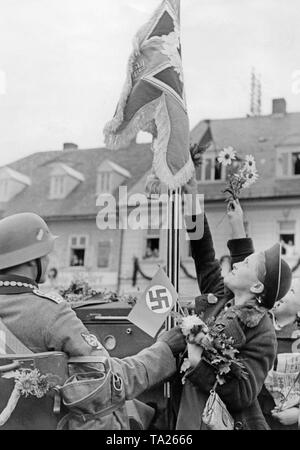 German troops march on October 2, 1938, in the town of Schluckenau (today Sluknov).  A girl reaches for the standard of a motorized detachment. Stock Photo