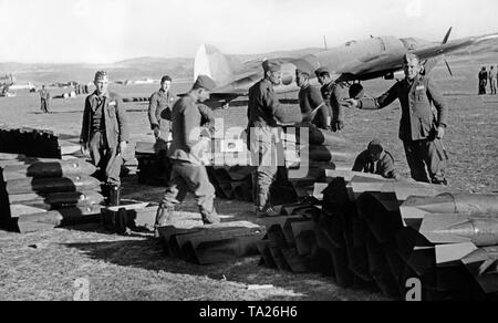 Photo of a group of soldiers of the ground personnel of the Condor Legion preparing 250kg pilot bombs on an airfield of the unit. In the background, a fighter bomber, type Heinkel He 111. Stock Photo