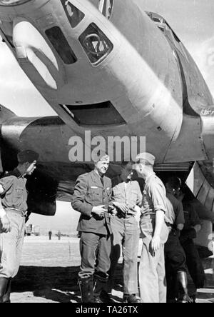 Photo of a Major of the Combat Group 88 of the Condor Legion in conversation with soldiers of the ground personnel at an airfield in Spain. The soldiers are standing under the hull of a Heinkel He 111 bomber. In the upper edge of the photo, the forward gunner compartment, which was made of plexiglass. Stock Photo