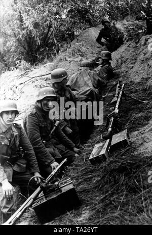 German soldiers rest in a trench during a pause in the fighting. In front of them, several rifles and a Maschinengewehr 34 on hand. Photo of the Propaganda Company (PK): war correspondent Lachmann. Stock Photo