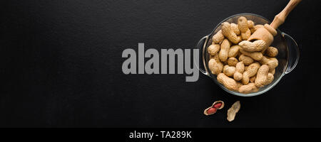 Bowl with peanuts on black Stock Photo