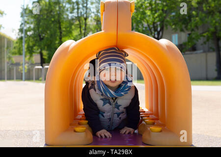 Child playing in playground, walking trough tunnel Stock Photo