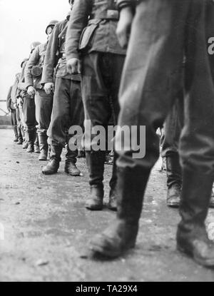 Wehrmacht soldiers with marching boots and gas masks stand in row during a training. Stock Photo