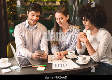 Business team on meeting discussing project with smartphone in cafe Stock Photo