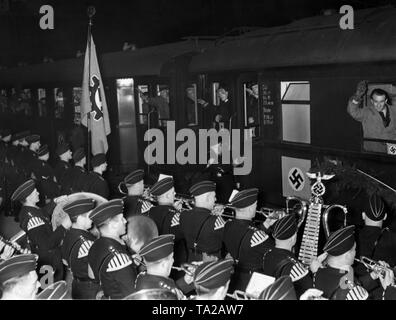 After the Anschluss of Austria, Austrian workers participate in a Germany tour organized by the Nazi organization 'Kraft durch Freude', here on arrival at the Muenchen Hauptbahnhof. In the foreground, a music band. On the left, a flag of the German Labor Front. Stock Photo