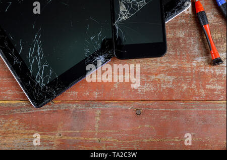 Repair tablet and smart phone with broken touch screen on wooden desk Stock Photo