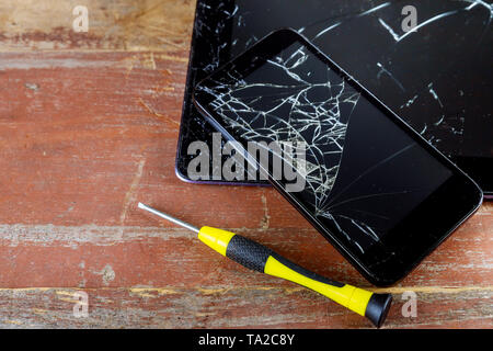 Broken smart phone and tablet on cracked touch screen process of mobile phone repair. Stock Photo