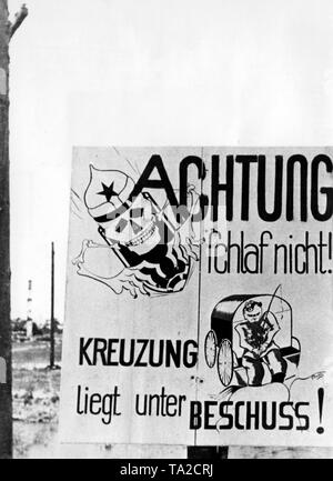 A street sign on the road warns arriving soldiers on possible enemy fire. Photo of the Propaganda Company (PK): war correspondent Schultze. Stock Photo