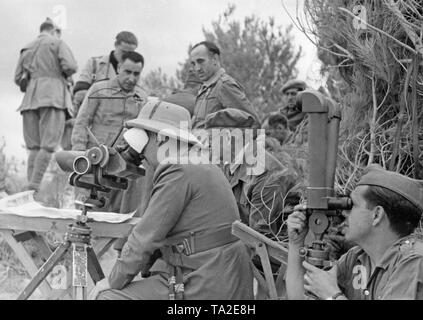 Photo of Generalissimo Francisco Franco (in the front with a topee, looking through a German headlight 35, Flakglas 10x80) together with General Emilio Mola Vidal (behind, with a beret and field tunic) during the visit of officers of a division of the Condor Legion in the Spanish Civil War before June, 1937. A legionary is looking through a scissors telescope. Behind the generals, a card table and staff officers. Stock Photo